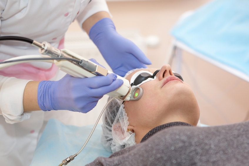 Woman having a laser skin treatment in a skincare clinic, a resurfacing technique for wrinkles, scars and solar damage to the skin of her face